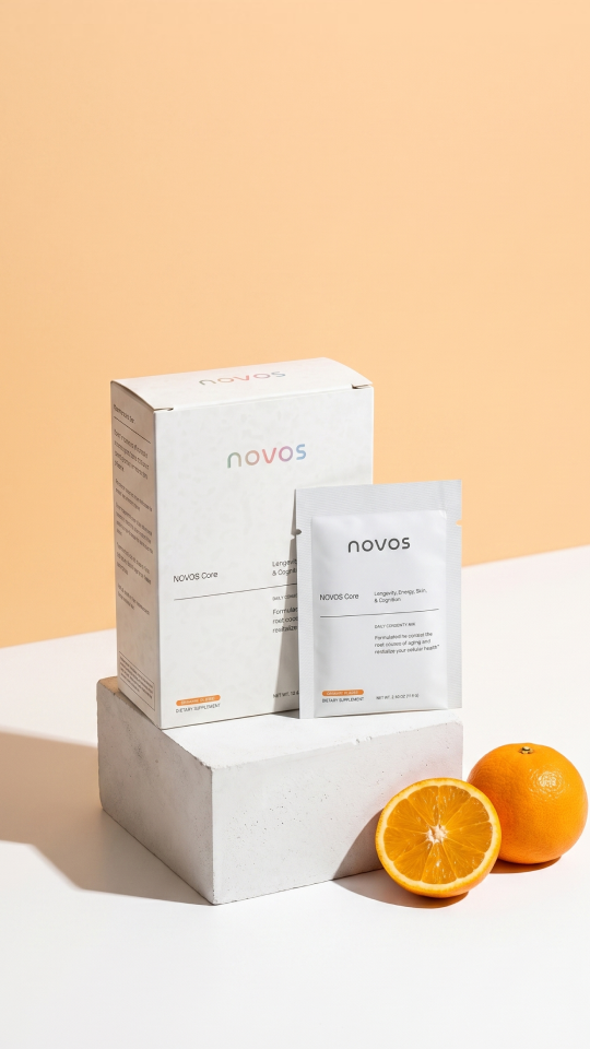 NOVOS Core box and sachet next to a glass of orange drink