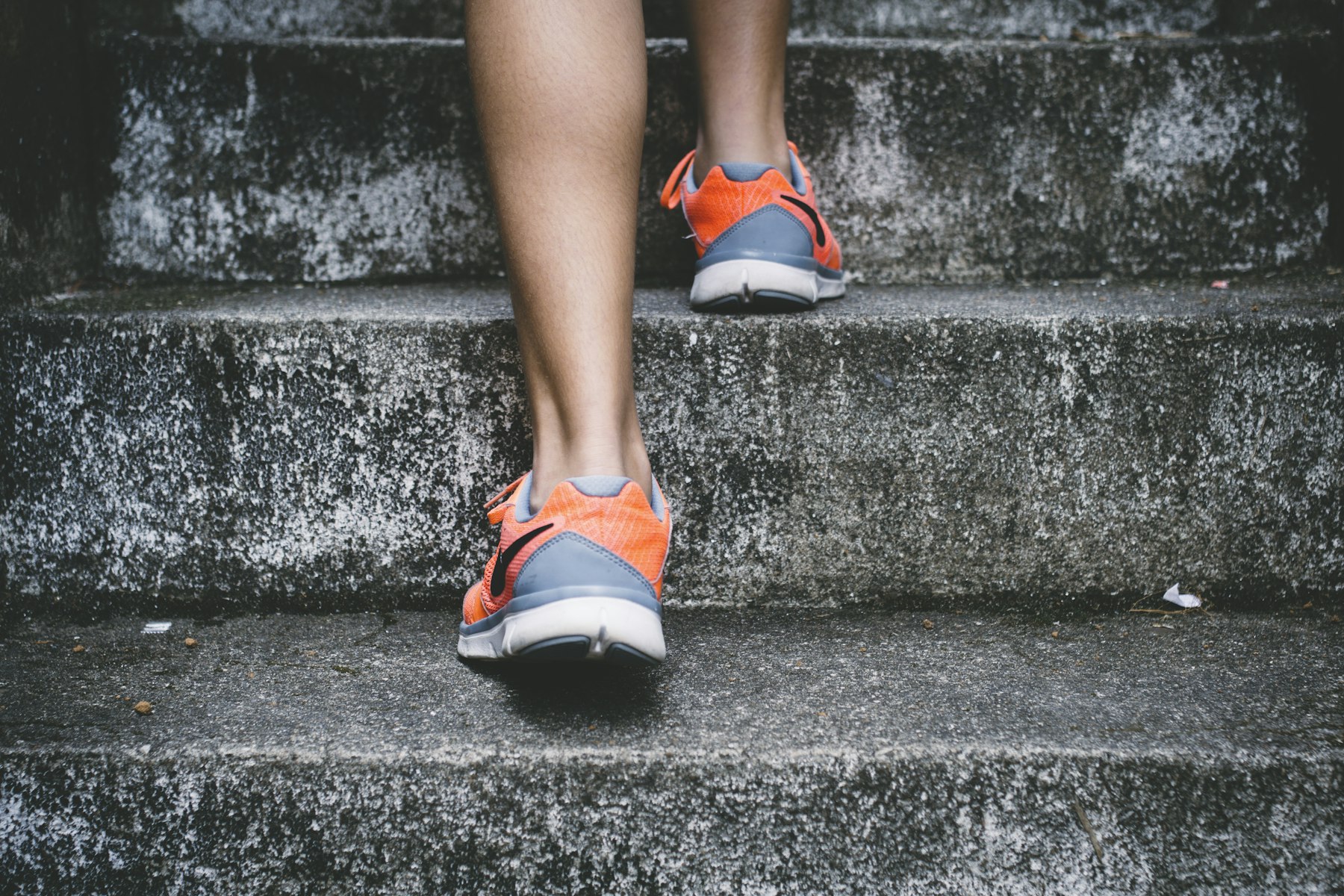 Active adult running up outdoor stairs in training shoes
