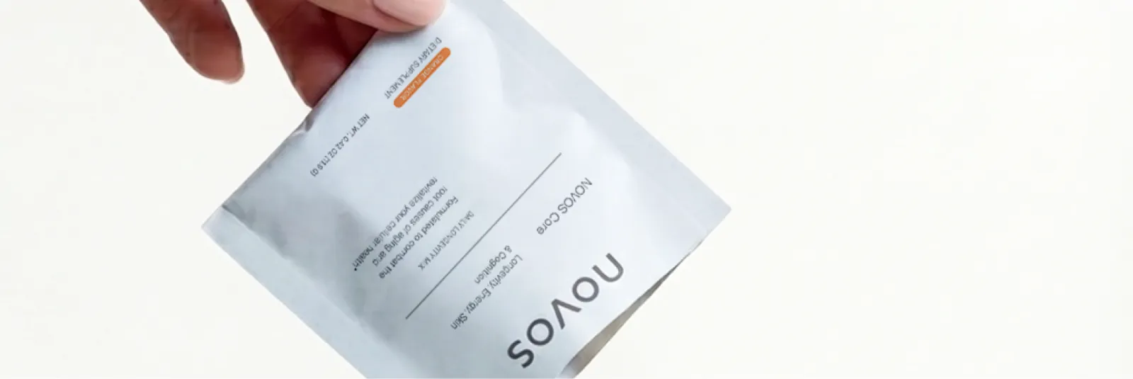 A hand holding a daily NOVOS Core sachet