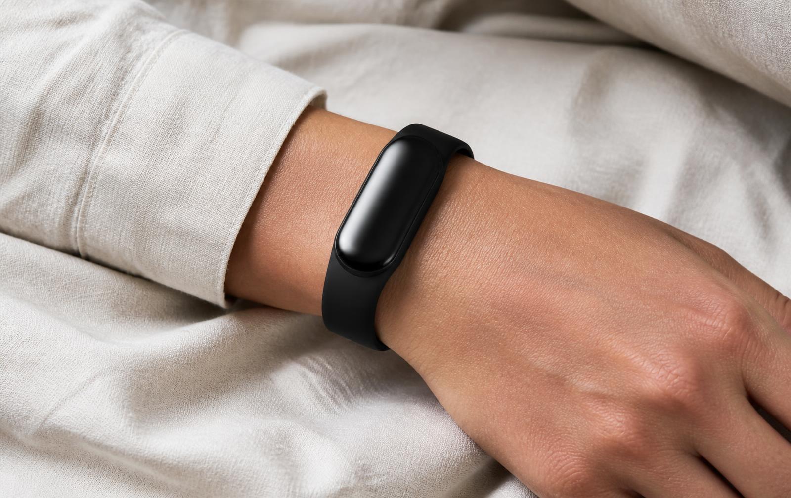 A sleep tracking band worn naturally on a wrist resting on linen