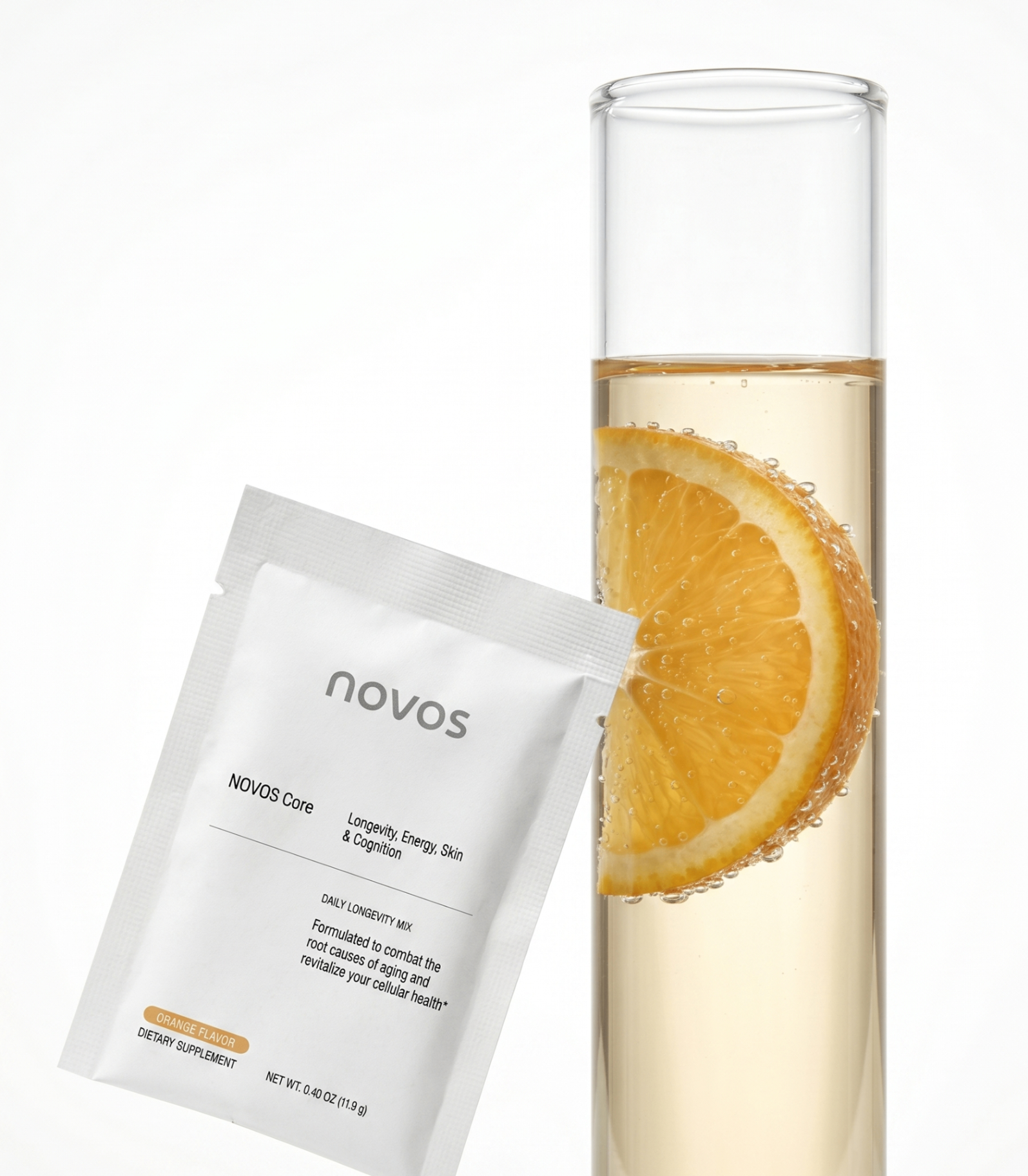 NOVOS Core sachet beside a tall glass of orange-infused drink